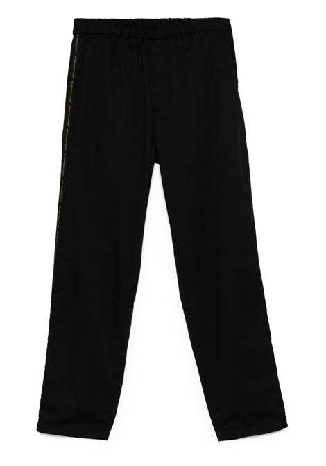 Black logo tape-detail trousers Undercover - men UNDERCOVER | Trousers | UP1E45021BLK